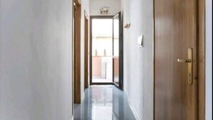 A narrow hallway with a wooden door on the right and a glass door at the end leading outside. - ENTIRE VACATION HOME BARI SARDO Iun.gov.it Q0005 (Bari Sardo)
