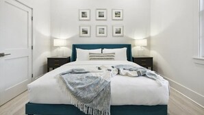 A neatly arranged bedroom with a bed, bedside tables, and framed pictures on the wall. - Bay St Louis Condos, Old Town BSL (Bay St Louis)