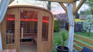 A wooden sauna with a glass door, a wooden bench inside, and a small potted plant outside. - Osada Natura - houses in Scandinavian style, Sauna and Jacuzzi family-friendly (Sliwin)