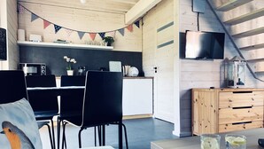 A modern kitchen with a microwave, coffee maker, and a small plant. There is a dining area with a table and chairs, and a wooden cabinet with drawers. - Osada Natura - houses in Scandinavian style, Sauna and Jacuzzi family-friendly (Sliwin)