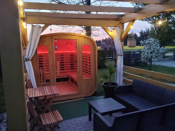A wooden sauna with a red interior, a wooden bench, a table, and a sofa. - Osada Natura - houses in Scandinavian style, Sauna and Jacuzzi family-friendly (Sliwin)