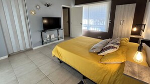 Ett sovrum med en säng, en tv på ett tv-bord, en garderob och ett fönster med utsikt.