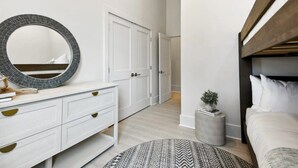 Un dormitorio con cama, mesita de noche, espejo, cómoda y armario.