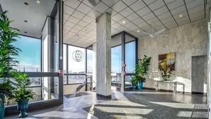A spacious lobby with large windows, marble walls, and potted plants. - Beautiful 2 Bedroom Condo At Century I With Indoor Pool (Ocean City)