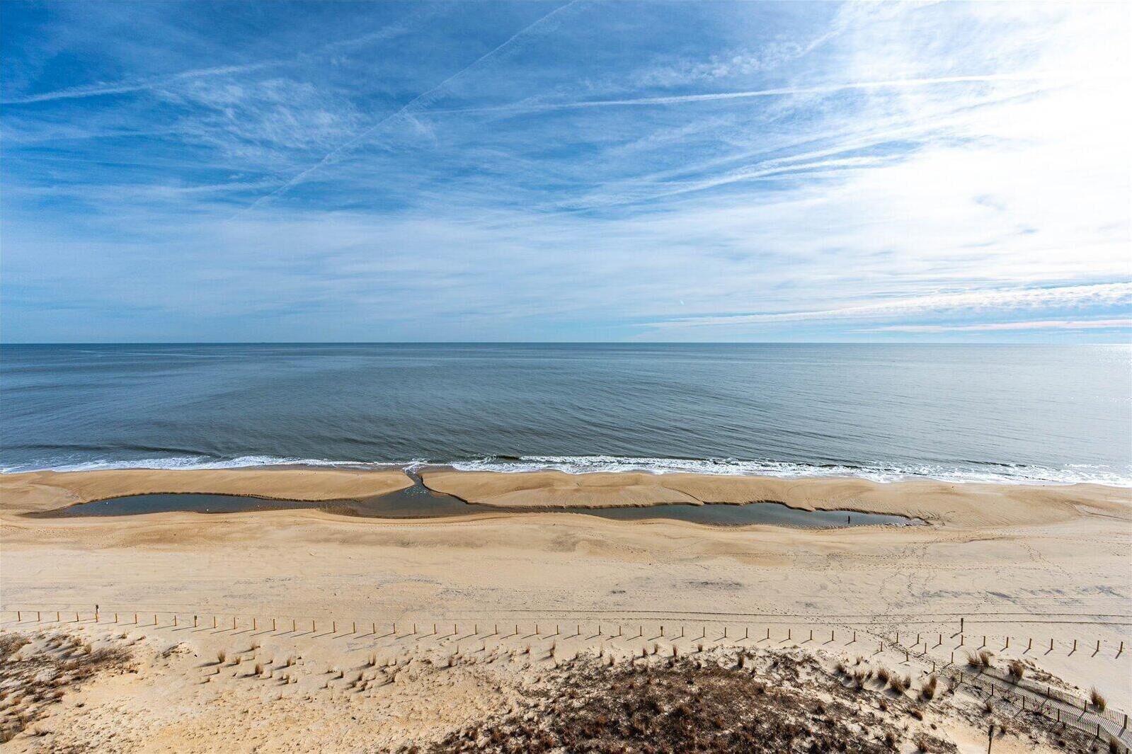 Ein Strand mit einer Umzäunung und spärlicher Vegetation.