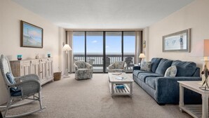 A spacious living room with a view of the ocean, a balcony, and a large window. - Century One-Sunny Oceanfront 2 bed/2 bath with Indoor Pool! (Ocean City)