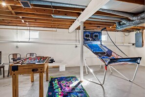Un espace de loisirs intérieur comprenant une table de baby-foot, un trampoline et une table de billard.