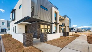 A modern two-story house with a stone facade, large windows, and a covered porch. - Paddle and Play: Desert Color Lagoon + Beaches (St George)