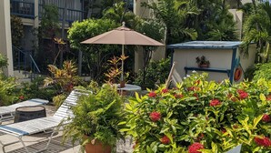 Une cour avec des fauteuils, une table ronde et un grand parasol.