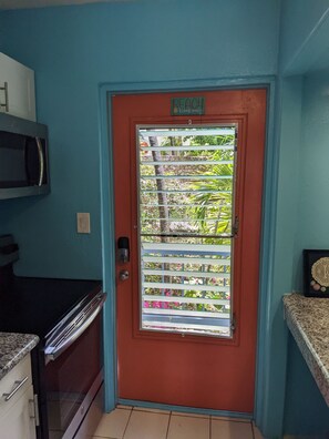 A kitchen with a red door, a microwave, and a stove. - SEA TURTLE COVE ST
CROIX -NO PASSPORT (Christiansted)
