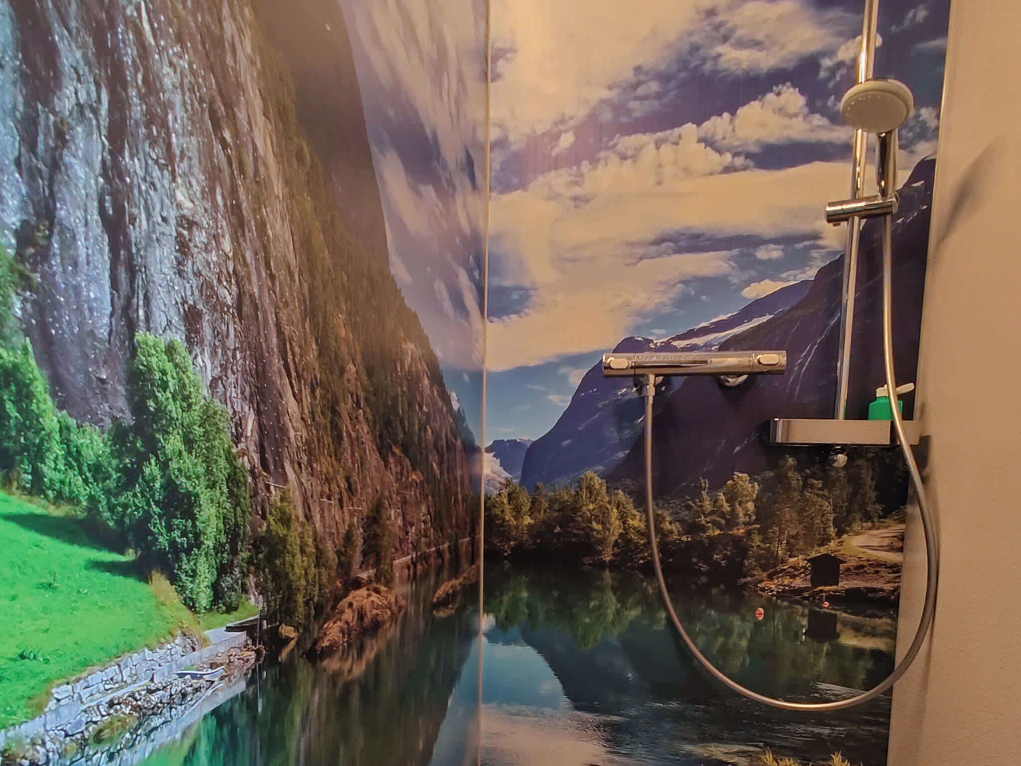 A bathroom with a large mirror reflecting a scenic view of a mountain and a river.