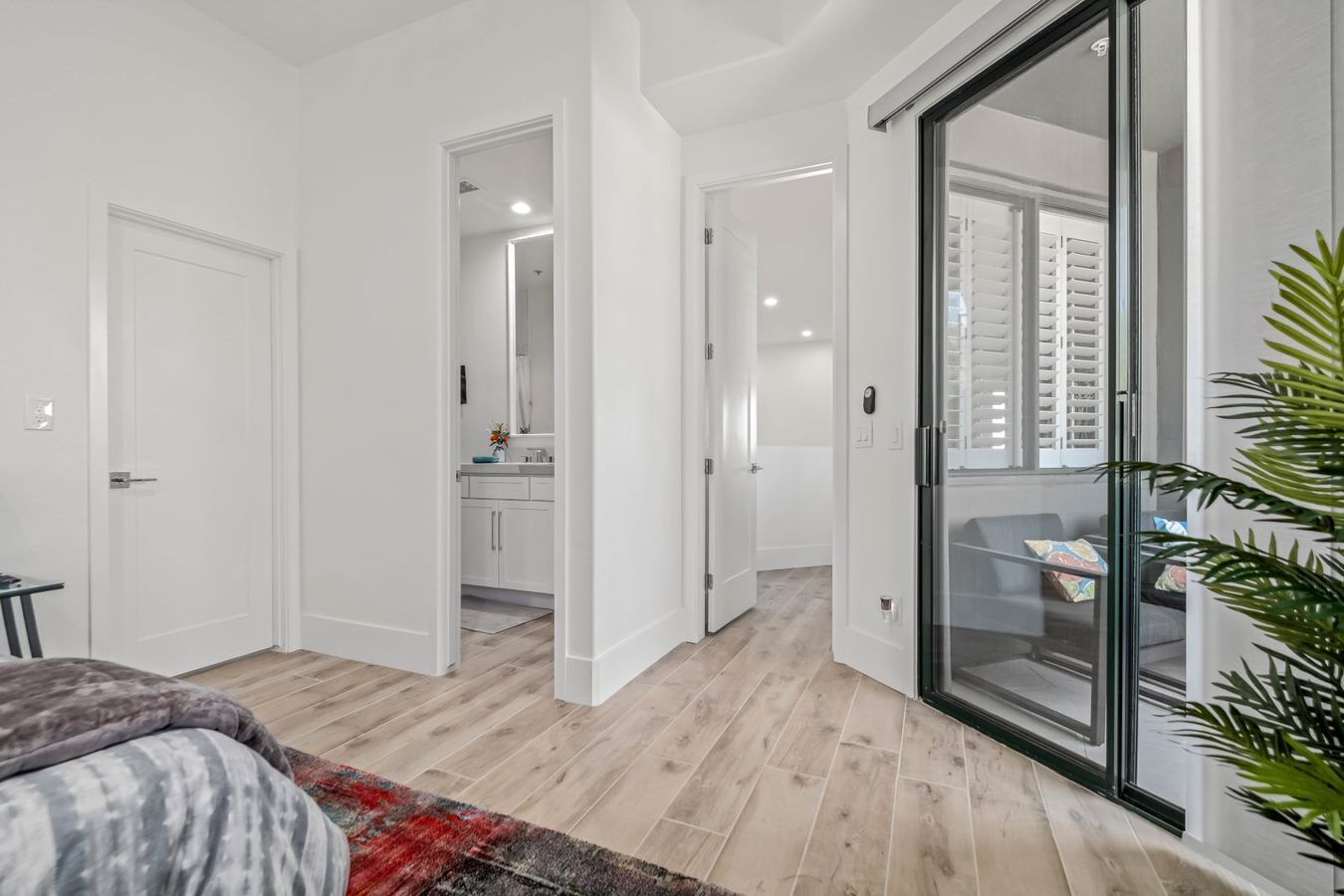 Un dormitorio moderno con una cama grande, un vidrio que da a un balcón y un baño visible con ducha y lavamanos.
