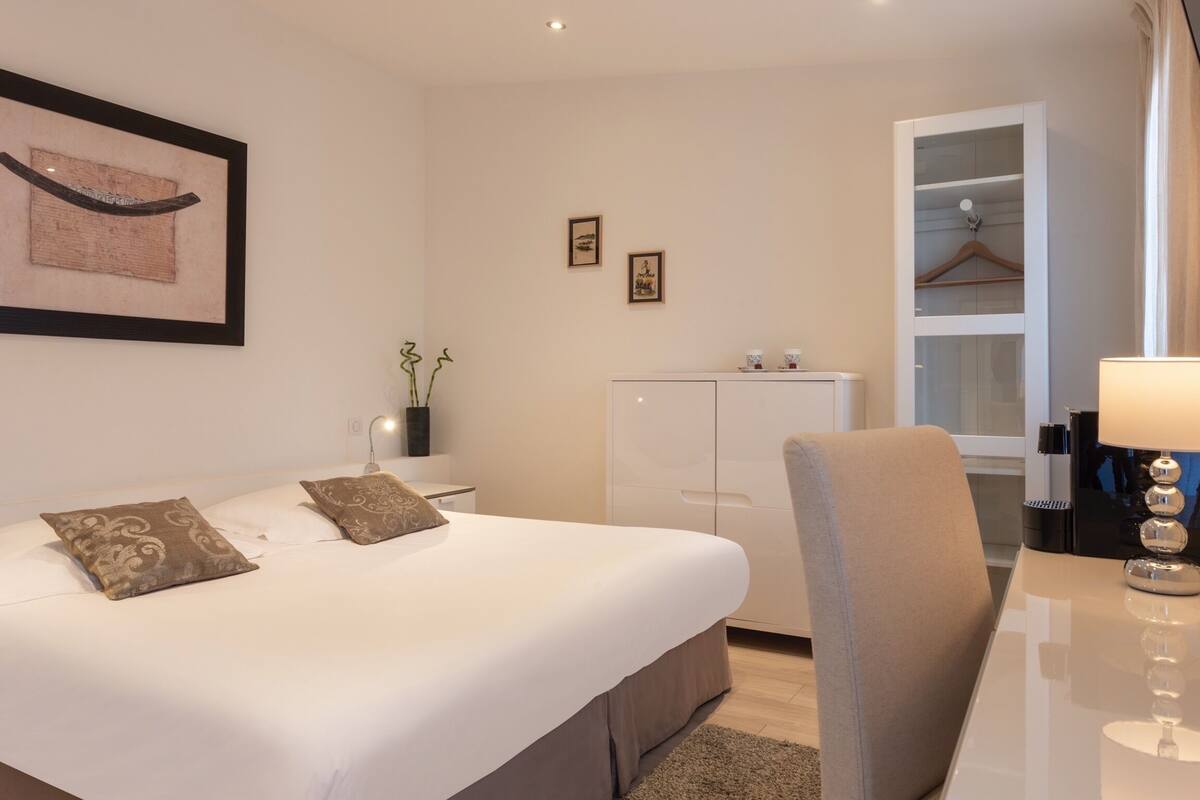 A bedroom with a bed, bedside table, lamp, and a wardrobe.