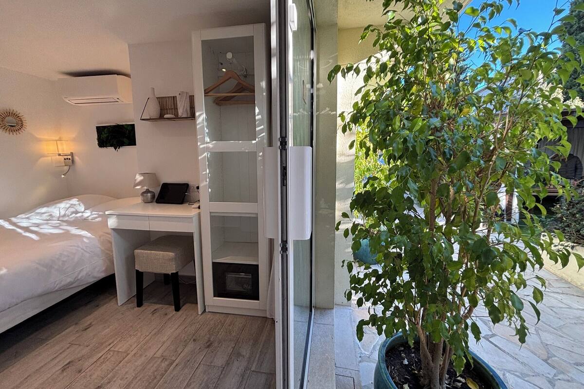 A bedroom with a bed, a desk, and a potted plant.