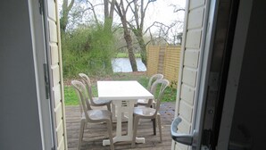Eine Terrasse im Freien mit einem weißen Tisch und vier Stühlen, umgeben von einem Holzboden und einem Holzzaun.
