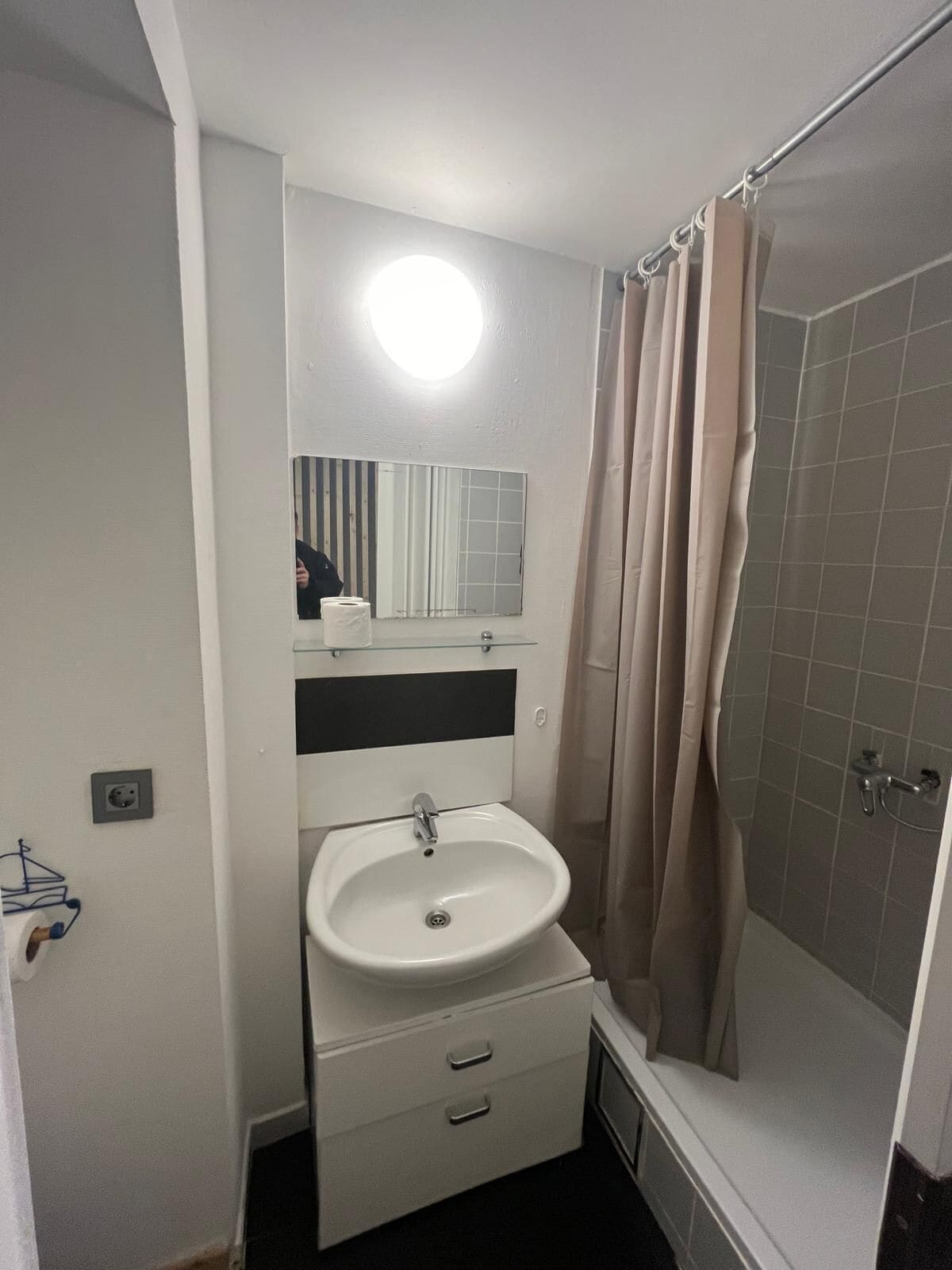 A compact bathroom with a white sink, a mirror, and a shower curtain.