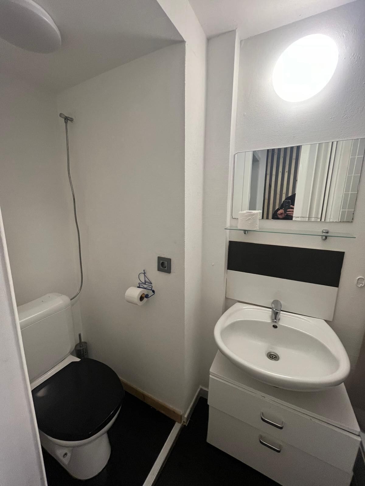 Une petite salle de bain compacte, équipée de toilettes, d’un lavabo et d’un miroir.