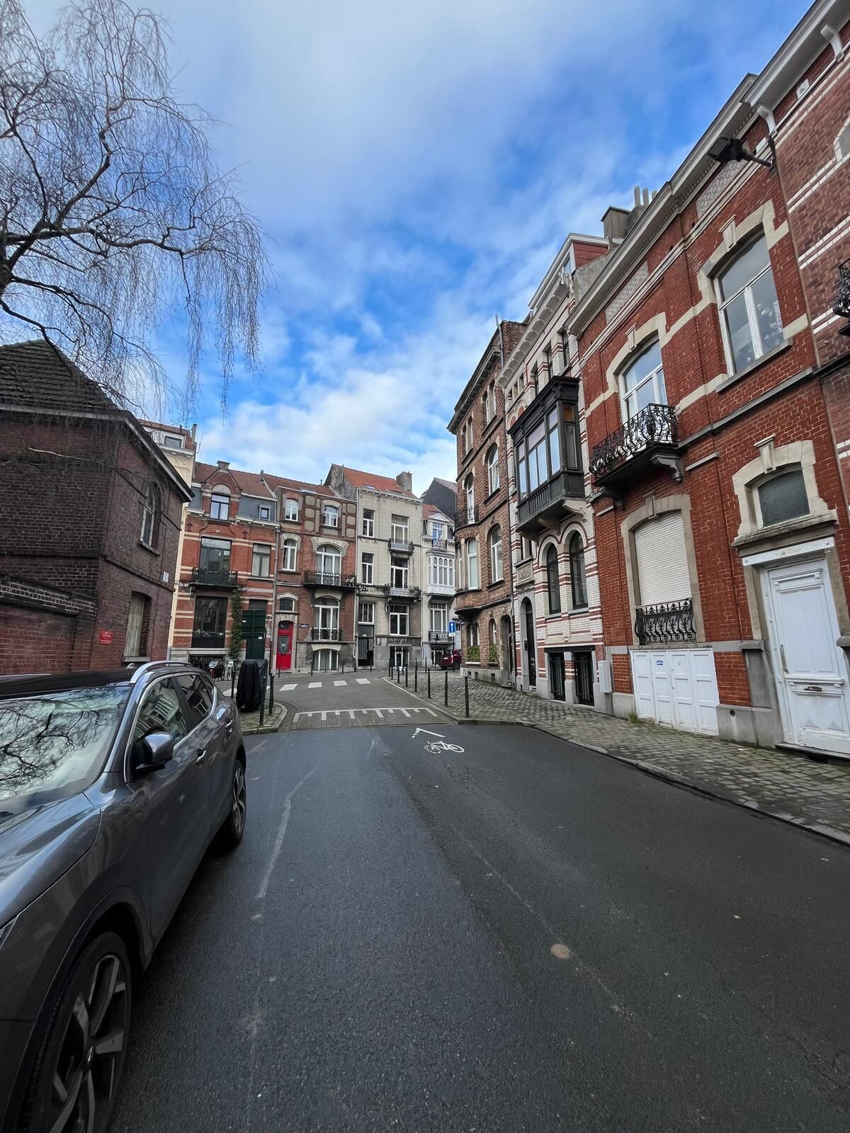 Uma rua com edifícios altos, alguns com varandas e janelas grandes.