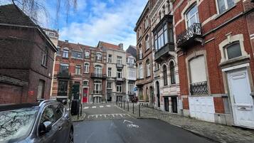 Uma rua com edifícios altos, alguns com varandas e janelas grandes.