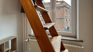 A wooden staircase leading to a window with a view of a brick building. - European District Studios (Brussels)