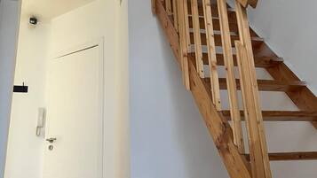 A wooden staircase with a handrail leading to a white door.