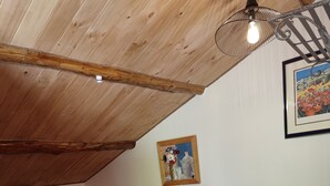 A bedroom with a sloped ceiling, a wooden headboard, two beds with red and green bedding, a small bedside table with a lamp, and a framed painting on the wall. - En Pleine Nature Mas Cévenol Calme Sans vis à Vis, Baignade à Proximité (BREAU-MARS)