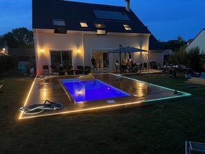 Une maison avec une piscine, un espace extérieur aménagé pour s’asseoir et une terrasse couverte.