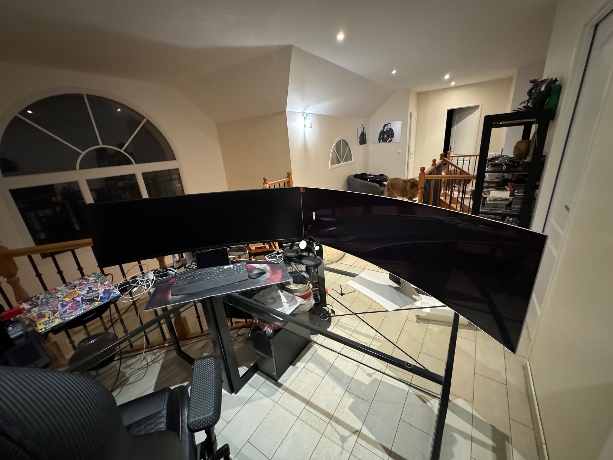 Una oficina en casa con un escritorio, computadora y silla. Una escalera conduce a una plataforma con vistas al exterior.