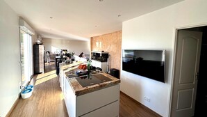 A modern kitchen with a large island, built-in appliances, and a dining area with a view. - Charming Family House with Garden and Heated Swimming Pool 1 hour from Paris (Méré)