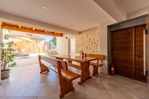 A spacious patio with a wooden table and benches, a fire extinguisher, and a stone wall. - Villa Izvor (Skradin)