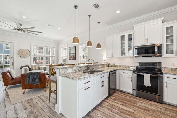 A spacious kitchen with white cabinetry, a large island, and modern appliances.