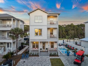 A two-story house with a front porch, a swimming pool, and a red ATV.