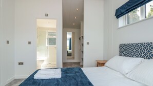 A bedroom with a large bed, a bedside table, and a window with a blue curtain. - Bluebell Lodge (Dartmouth)