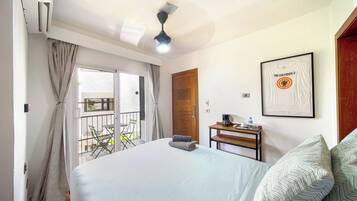 Une chambre d’hôtel avec un lit, une petite table sur laquelle se trouve une machine à café, un tableau encadré au mur et un balcon avec une table et des chaises.