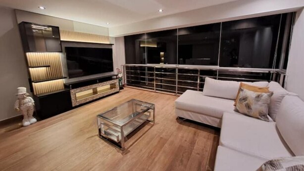 A modern living room with a large flat-screen TV, a glass coffee table, and a white sofa.