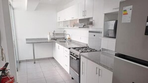 A modern kitchen with white cabinets, a stainless steel stove, and a refrigerator.