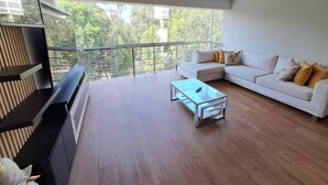 A modern living room with a large window, a white sofa, and a glass coffee table.