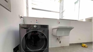A laundry area with a black washing machine and a white sink.
