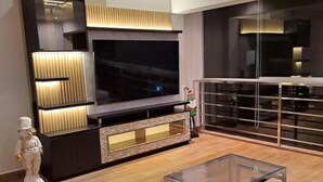 A modern living room with a large flat-screen TV, a glass coffee table, and a minimalist design.