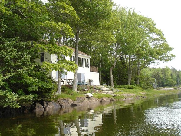 Un chalet au bord du lac, doté d’un quai, et entouré d’une forêt dense.