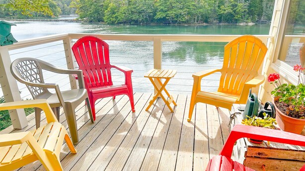 Une terrasse en bois avec des sièges extérieurs et une vue sur un lac.