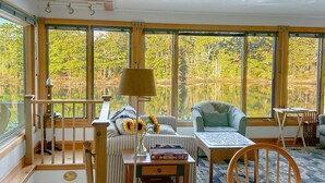 Une pièce avec vue sur un lac, un canapé, une table avec une lampe et une chaise.