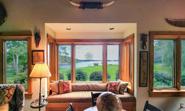 A cozy seating area with a view of a lake and greenery. - Experience coastal charm at Tidewatch in Boothbay, a spacious 3-bedroom home near the ocean. (Boothbay)