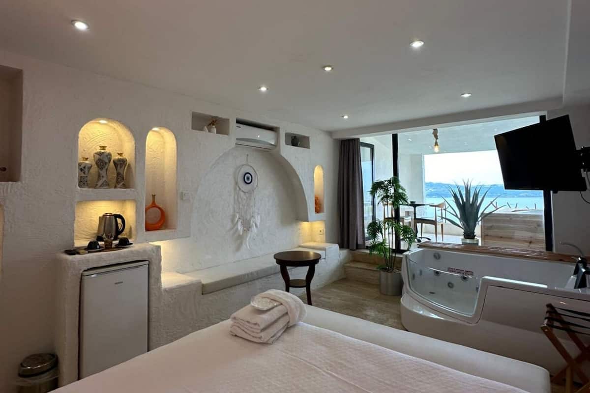 Habitació d'hotel moderna amb un llit gran, un escriptori petit, una banyera i vistes al mar.
