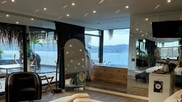 Een moderne hotelkamer met een groot bed, een zithoek met uitzicht op zee en een kleine kitchenette.