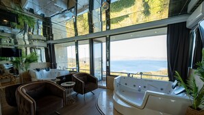 Een modern interieur met een groot raam, een jacuzzi en een zithoek met uitzicht op zee.
