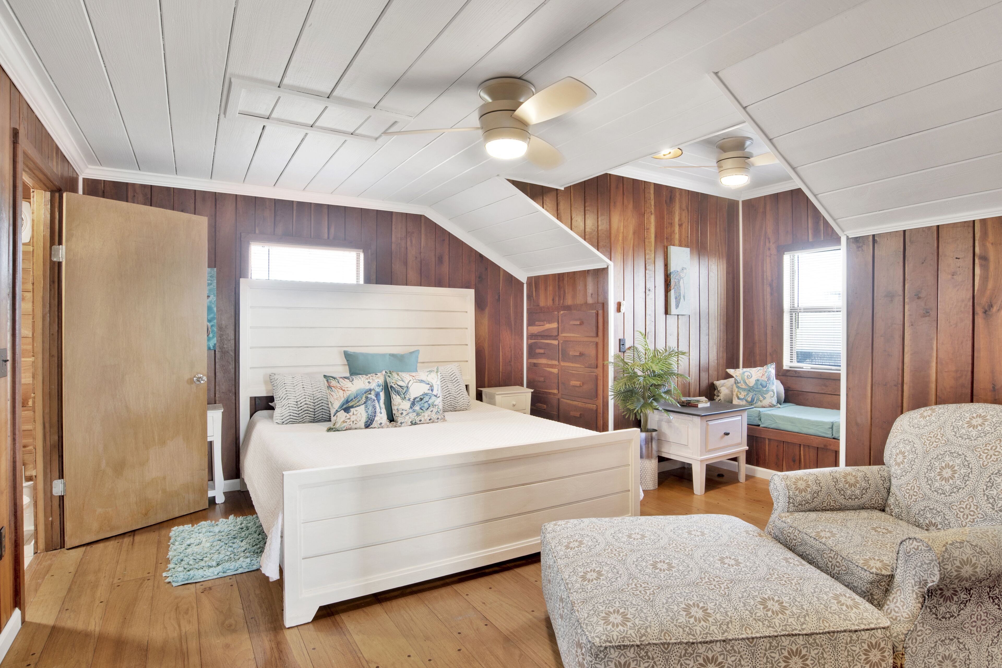 A bedroom with a large bed, a nightstand, a chair, and a window with a view.