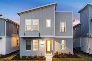 A modern two-story residential building with a front entrance, a small porch, and a well-maintained lawn. - The Boundless | Fab I-Drive home w/ unlimited entertainment - in-house and out! (Orlando)