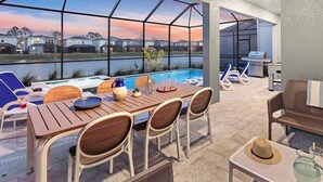 Un espace extérieur abrité comprenant une piscine, une table à manger et des chaises.