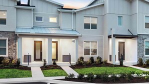 A modern multi-story residential building with a stone facade, multiple entry points, and a well-maintained lawn. - Fred's Funhouse | PVT pool, patio games, themed BR - near I-Drive entertainment (Orlando)
